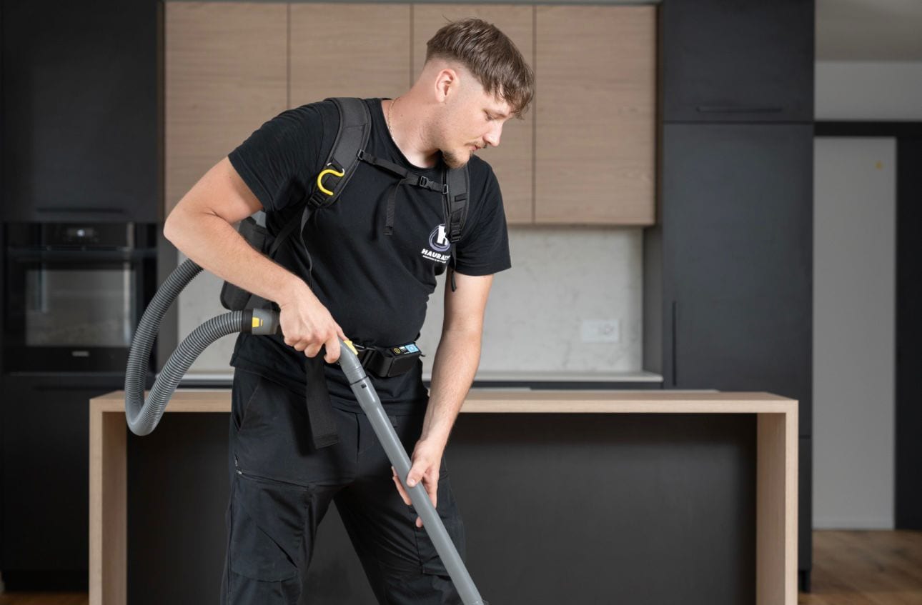 Collaborateur Hauralys passant l'aspirateur dorsal dans une cuisine contemporaine